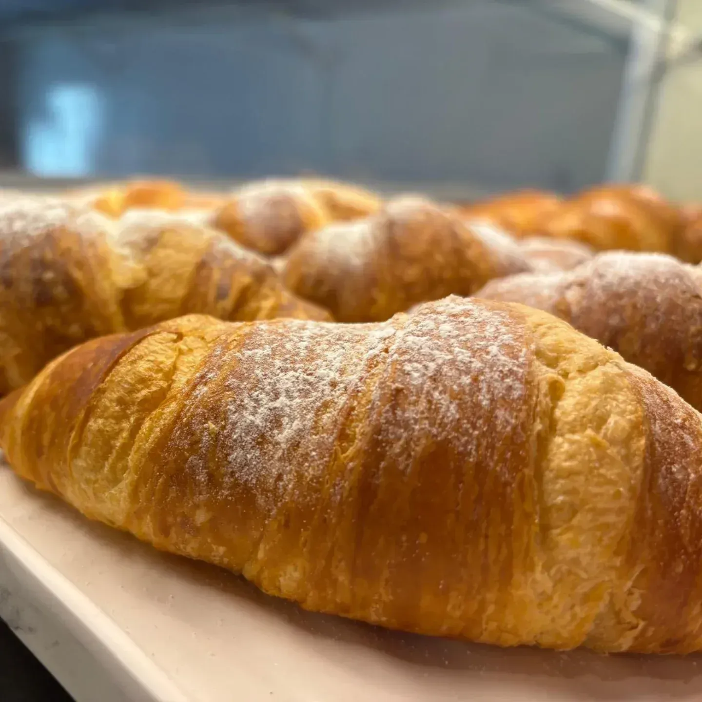 Primo piano di un croissant ricoperto di zucchero a velo su un tavolo.