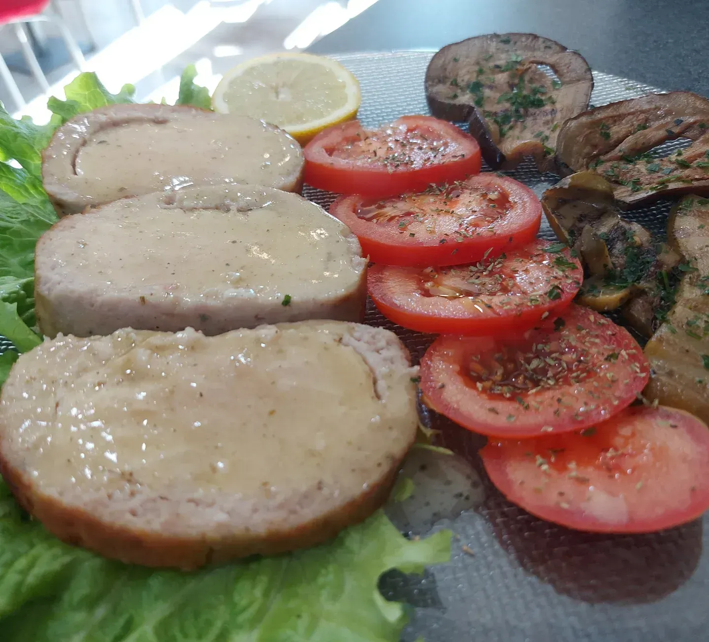 Un piatto di cibo con carne, pomodori e lattuga su un tavolo.