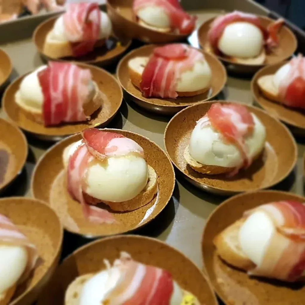 Un mucchio di piatti con sopra delle uova avvolte nella pancetta