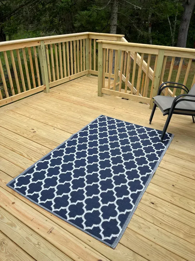 A blue and white rug is on a wooden deck.