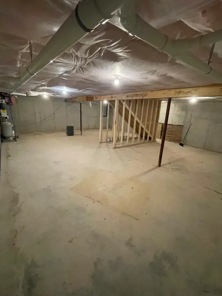 An empty basement with a ceiling and a staircase.