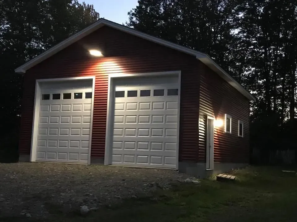 A red garage with white doors is lit up at night