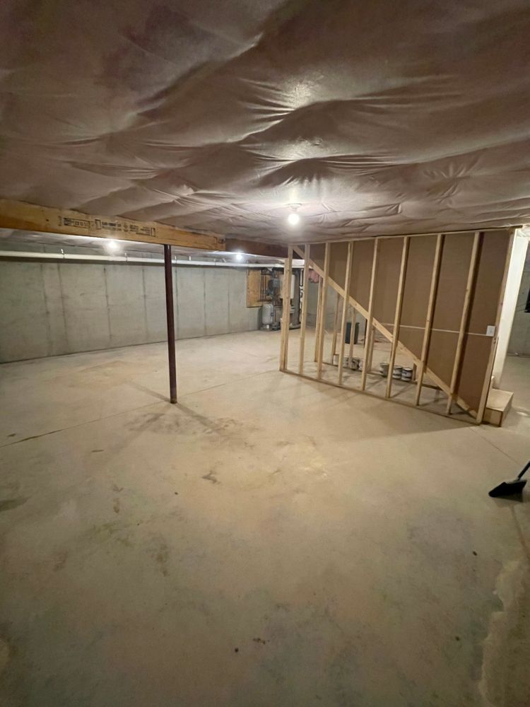 An empty basement with a staircase and a broom.