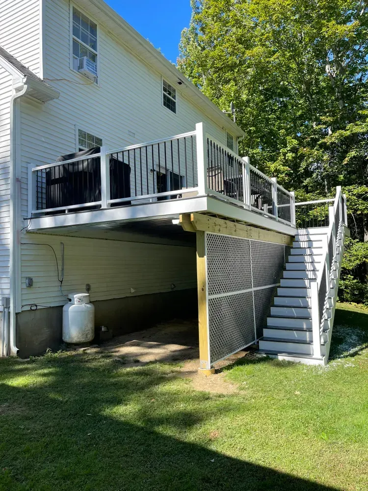 A white house with a deck and stairs in the backyard.