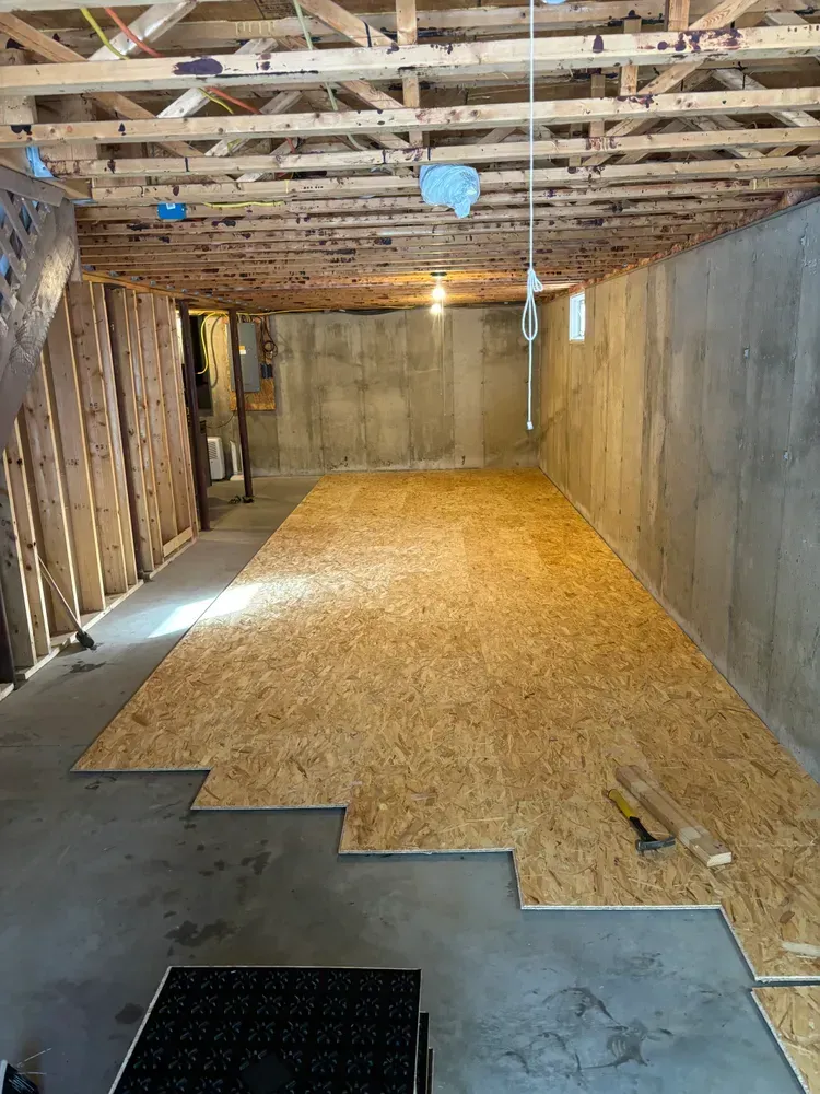 A basement with a wooden floor and a concrete wall.