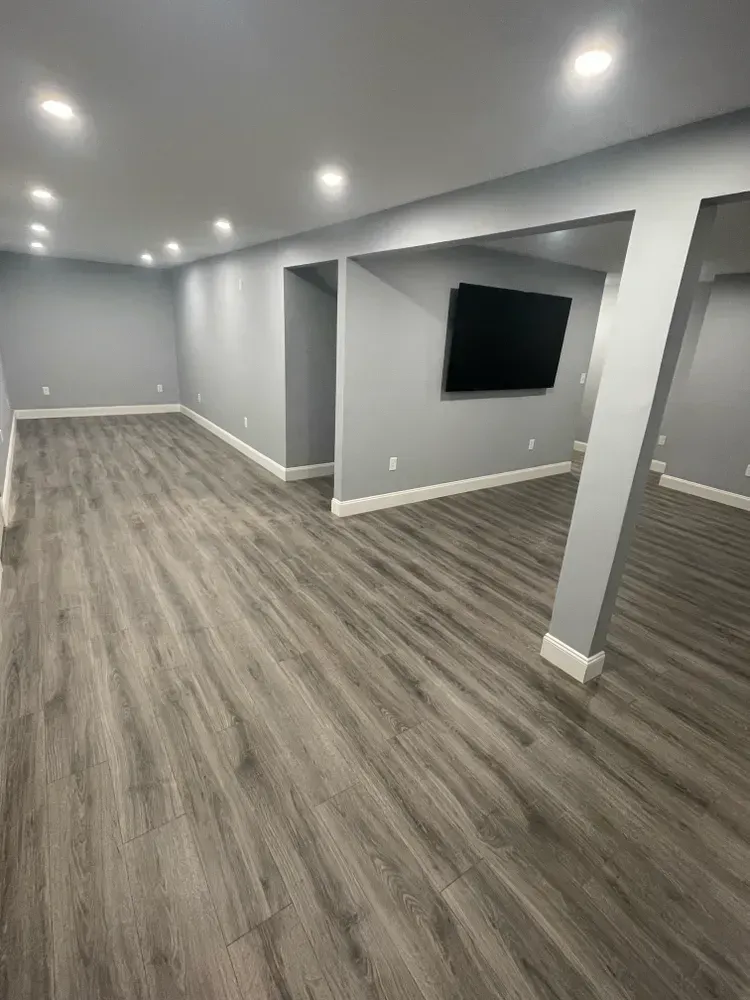 A basement with hardwood floors and a flat screen tv on the wall.
