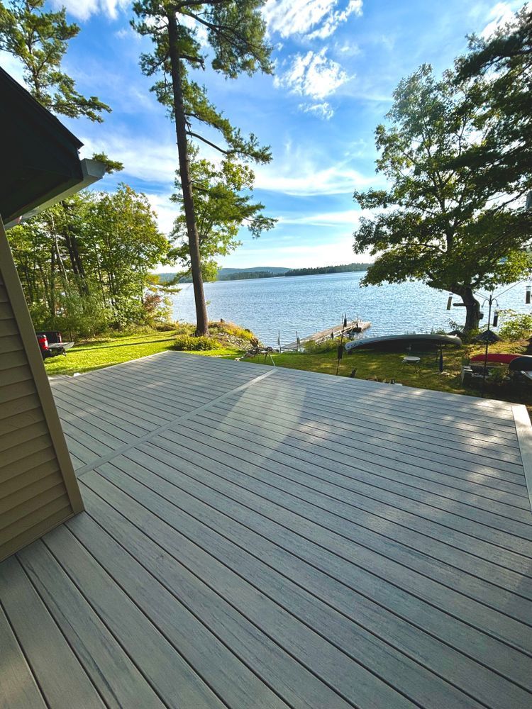 A deck overlooking a lake with trees in the background