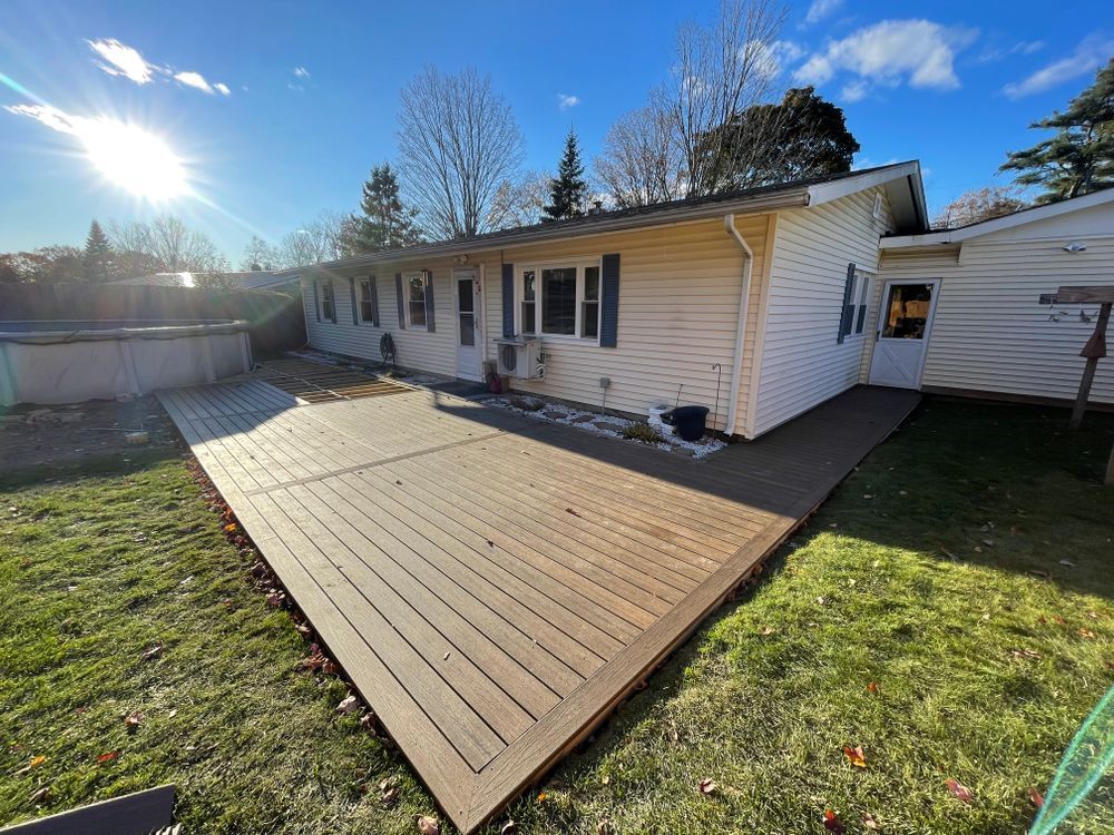 A white house with a wooden deck in front of it.