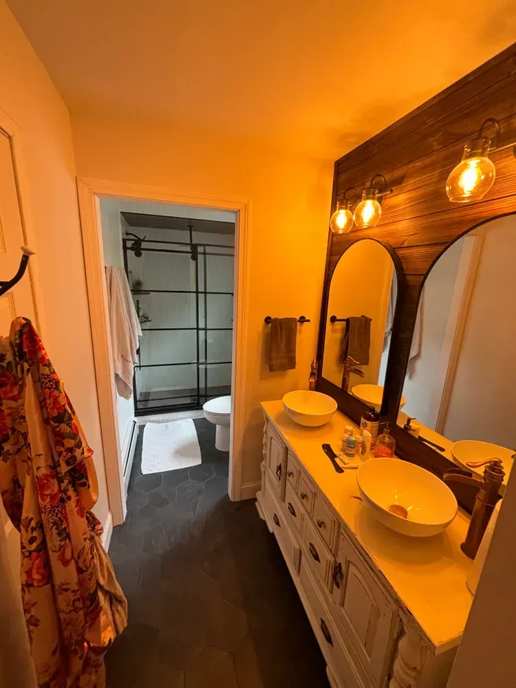 A bathroom with two sinks , a mirror and a toilet.