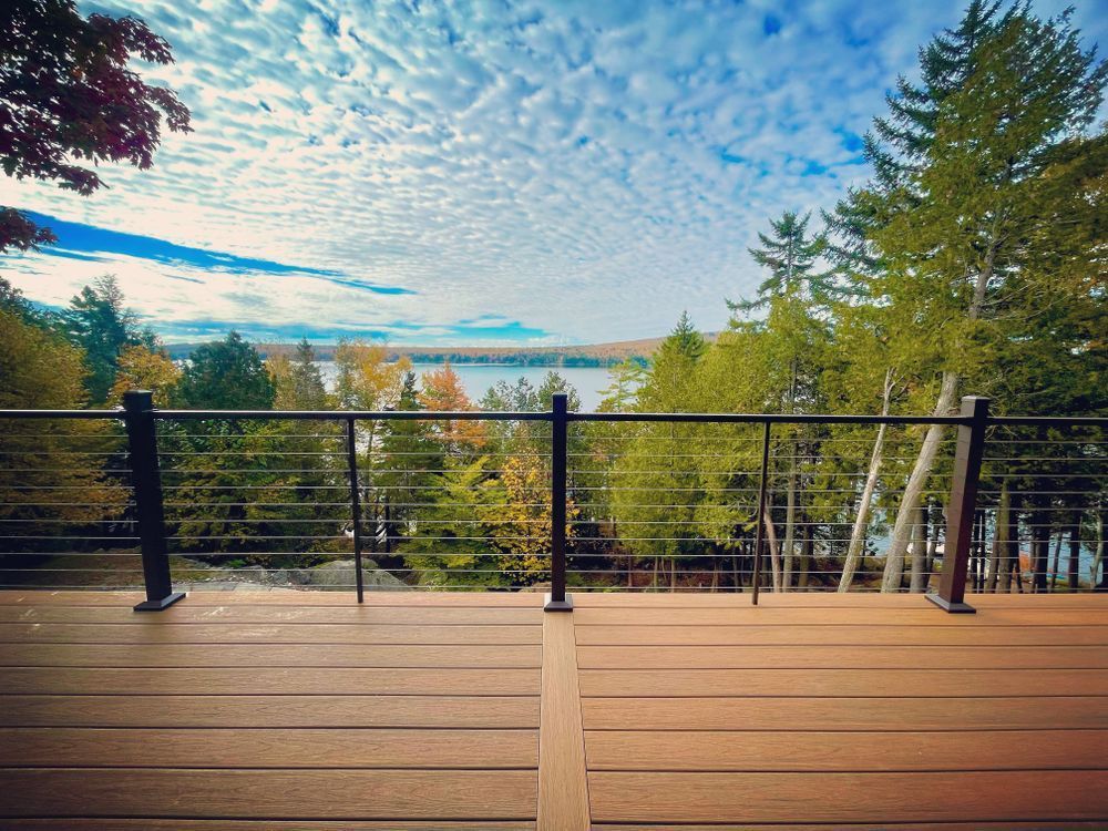 A wooden deck with a view of a lake and trees.
