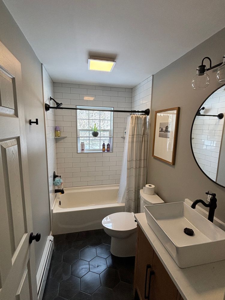 A bathroom with a sink , toilet , bathtub and mirror.