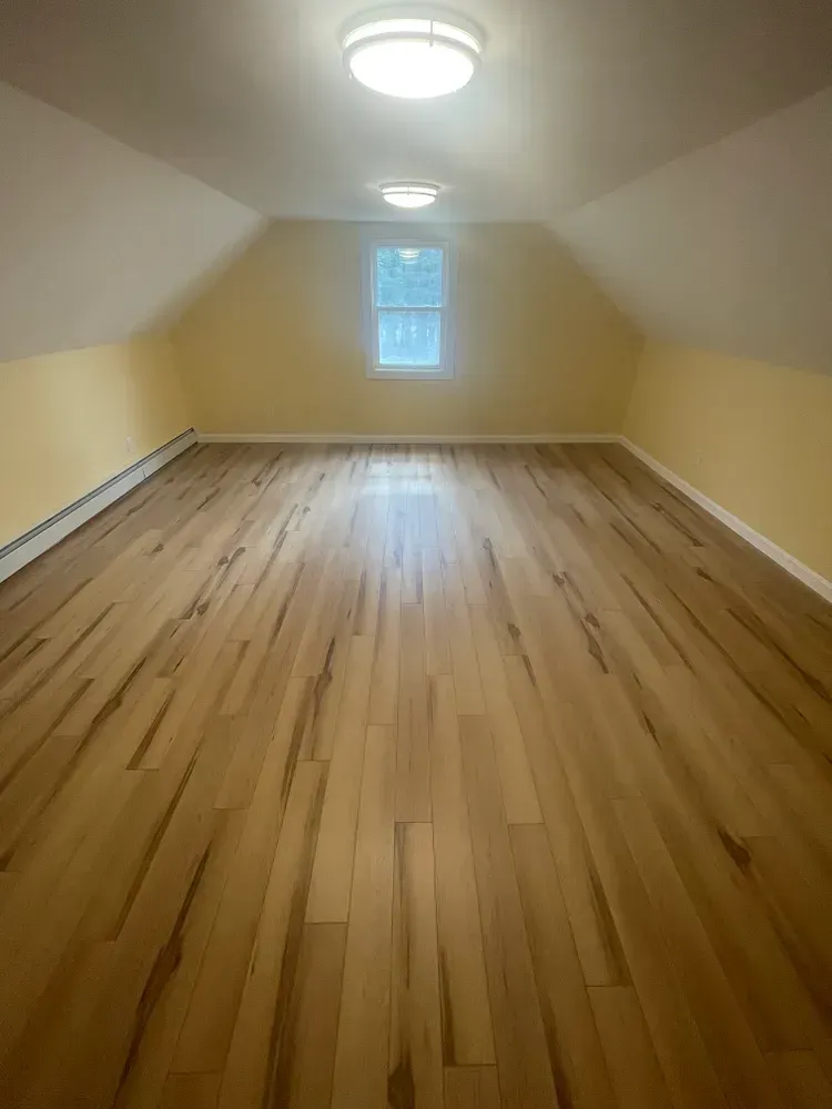 An empty room with hardwood floors and a window.