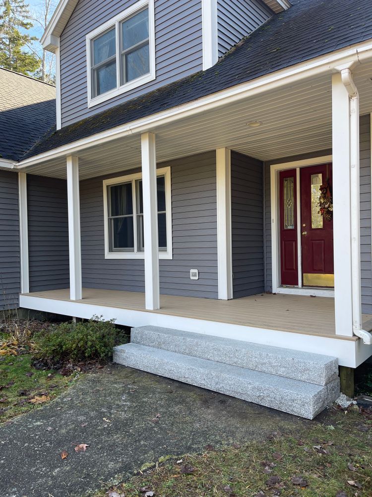 A gray house with a red door and a porch