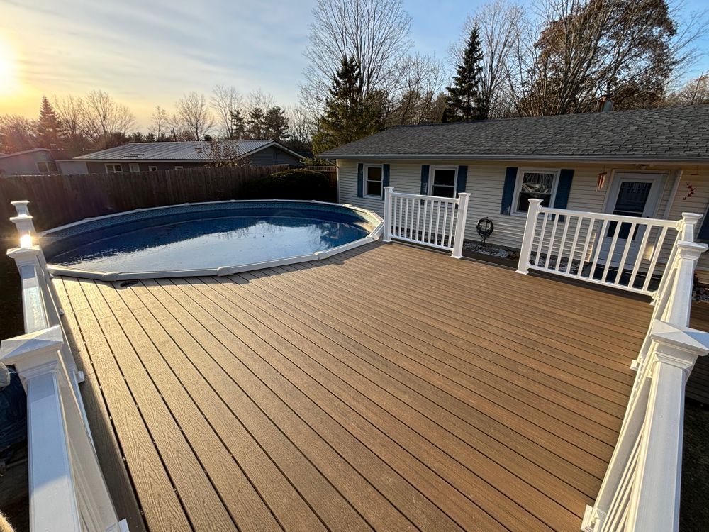 A large deck with a swimming pool in the backyard of a house.
