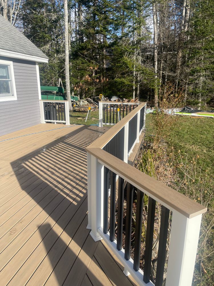 A wooden deck with a white railing and a house in the background.