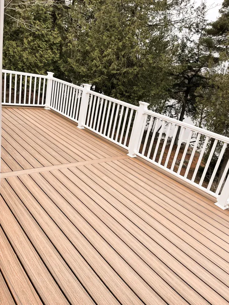 A wooden deck with a white railing overlooking a lake.