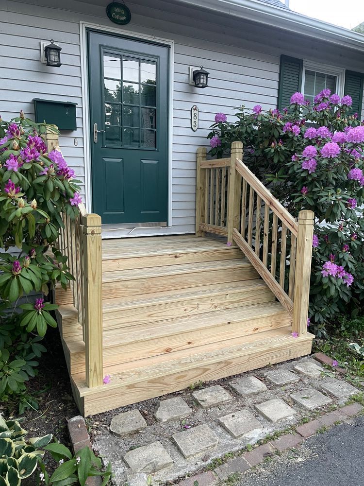 A wooden porch with stairs leading up to the front door of a house.