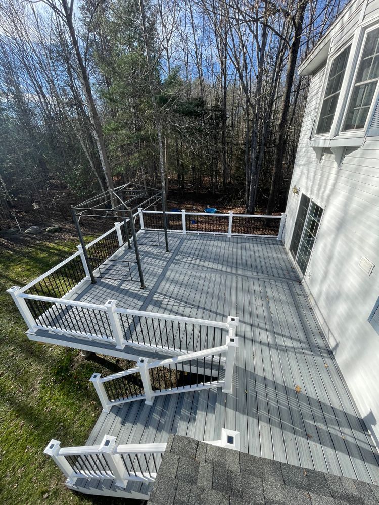 A large deck with a white railing is in the backyard of a house.
