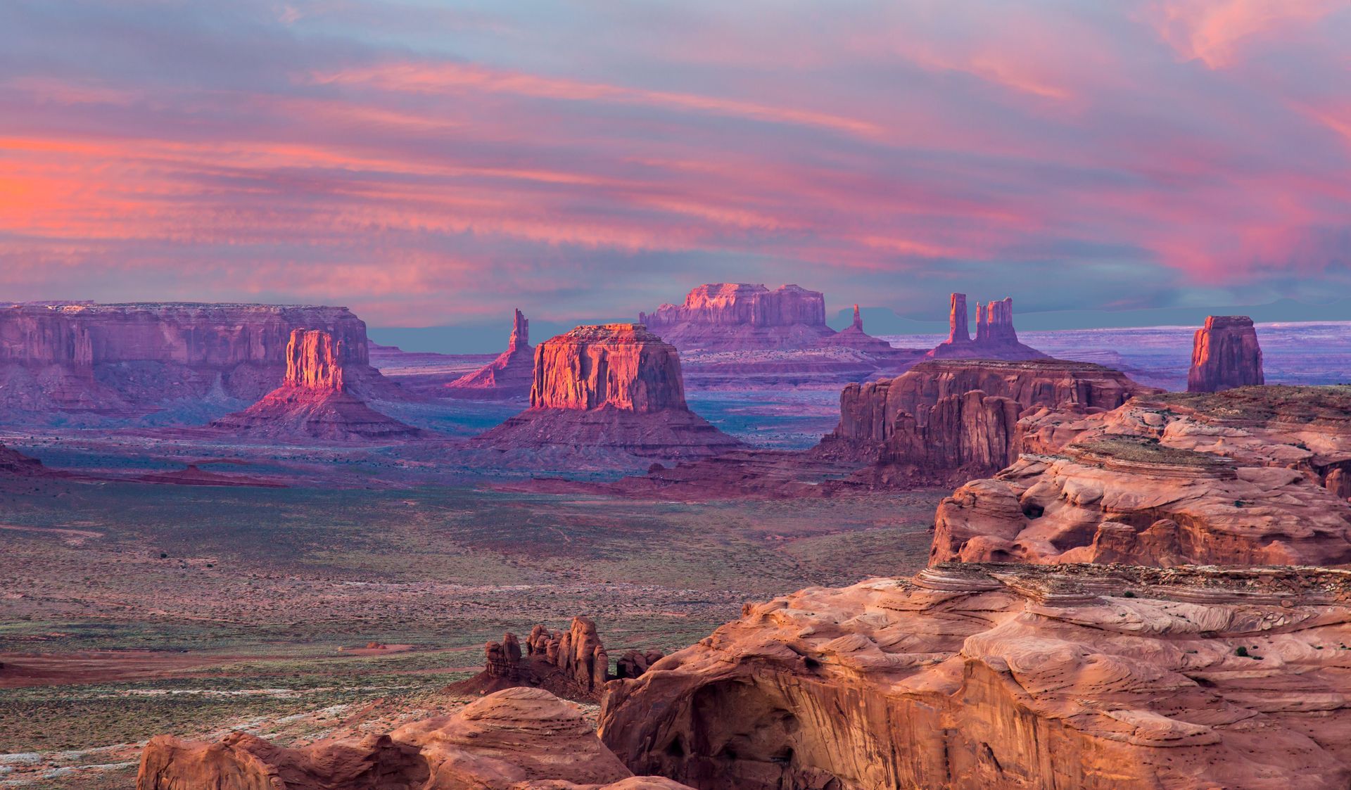 Sunset over Monument Valley: red rock formations, desert landscape, and colorful sky.