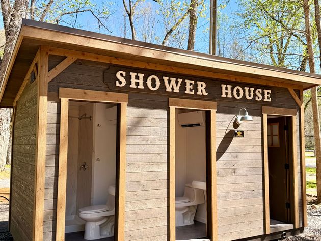 Wooden porch with rocking chairs, railing, and stairs, overlooking a grassy area and trees.