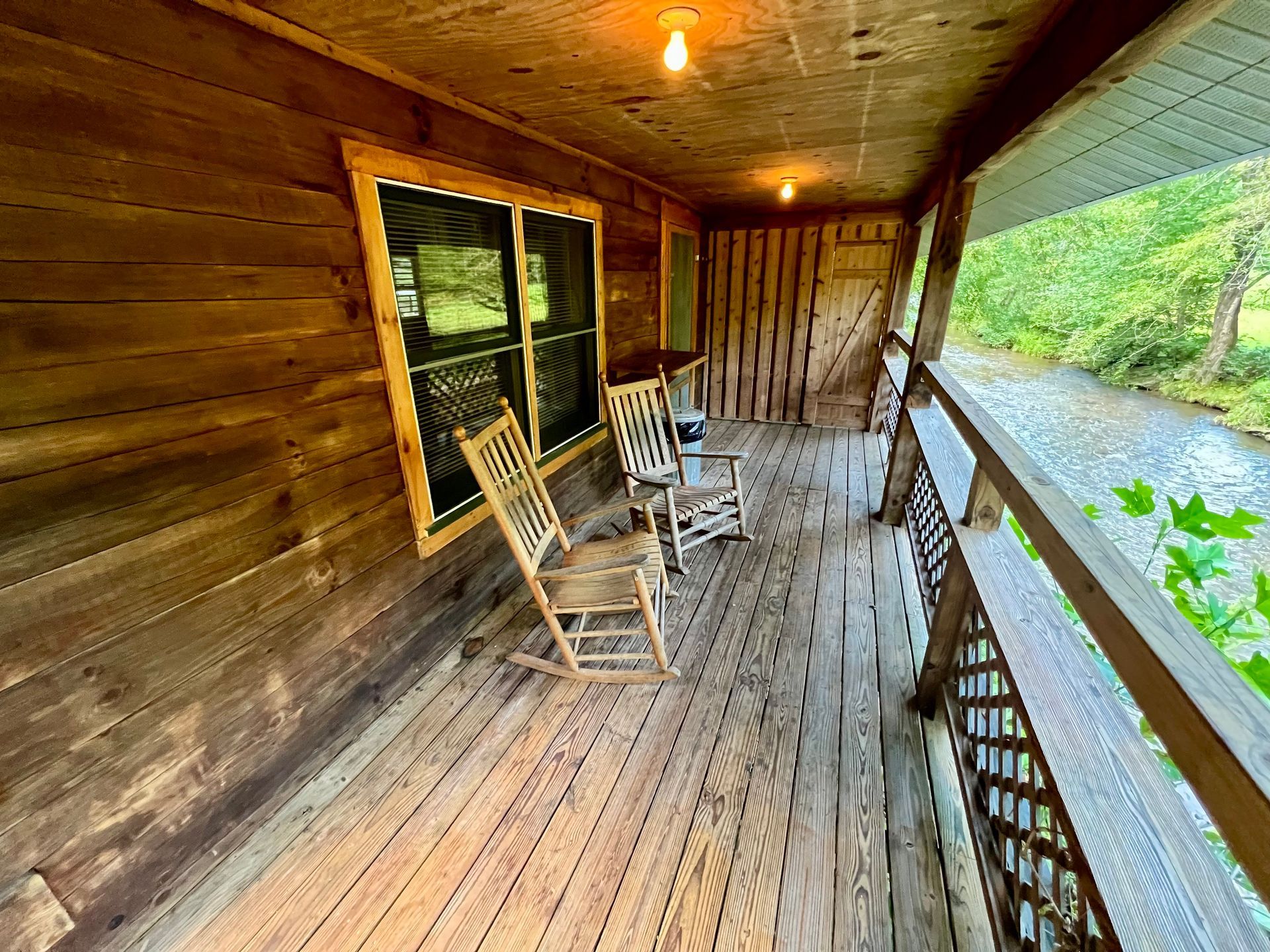 Wooden porch with two rocking chairs overlooking a flowing river.