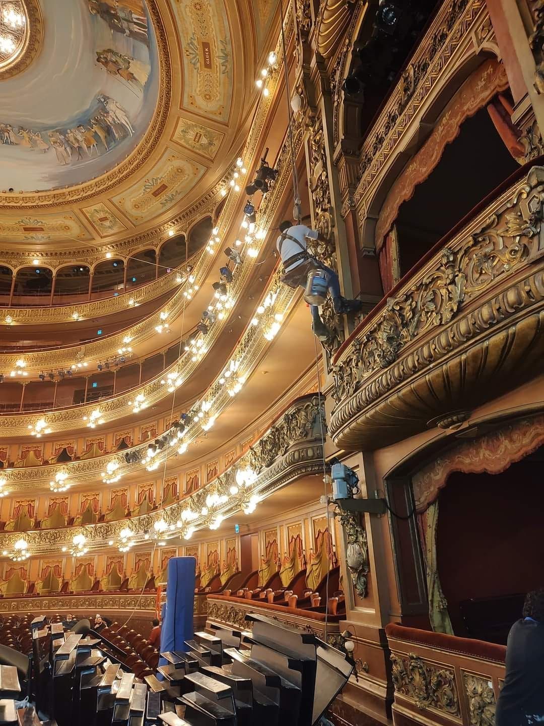 Interior de teatro ornamentado con múltiples balcones, detalles dorados y un techo pintado.