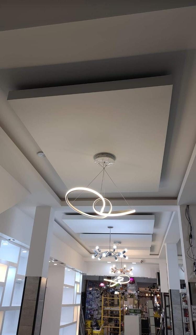 Interior de tienda de iluminación moderna con techo empotrado y luces colgantes.