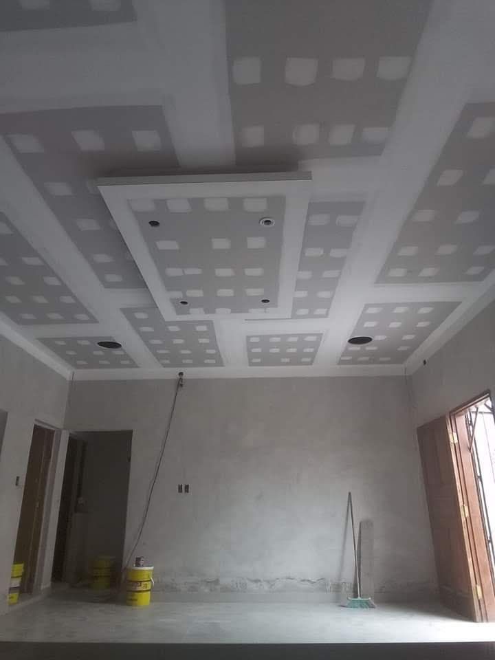 Habitación interior con techo de paneles de yeso sin terminar que presenta paneles empotrados.