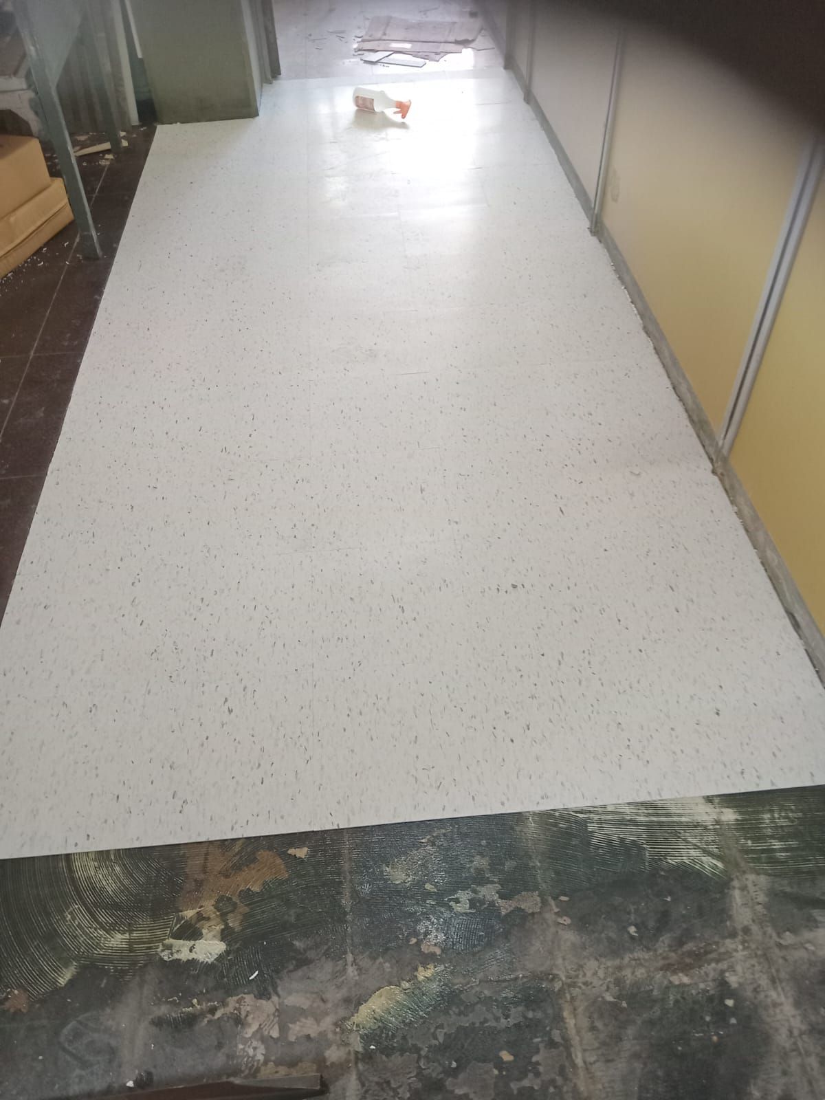 Pasillo largo con una superficie moteada de blanco que cubre el centro; las paredes son amarillas y grises.