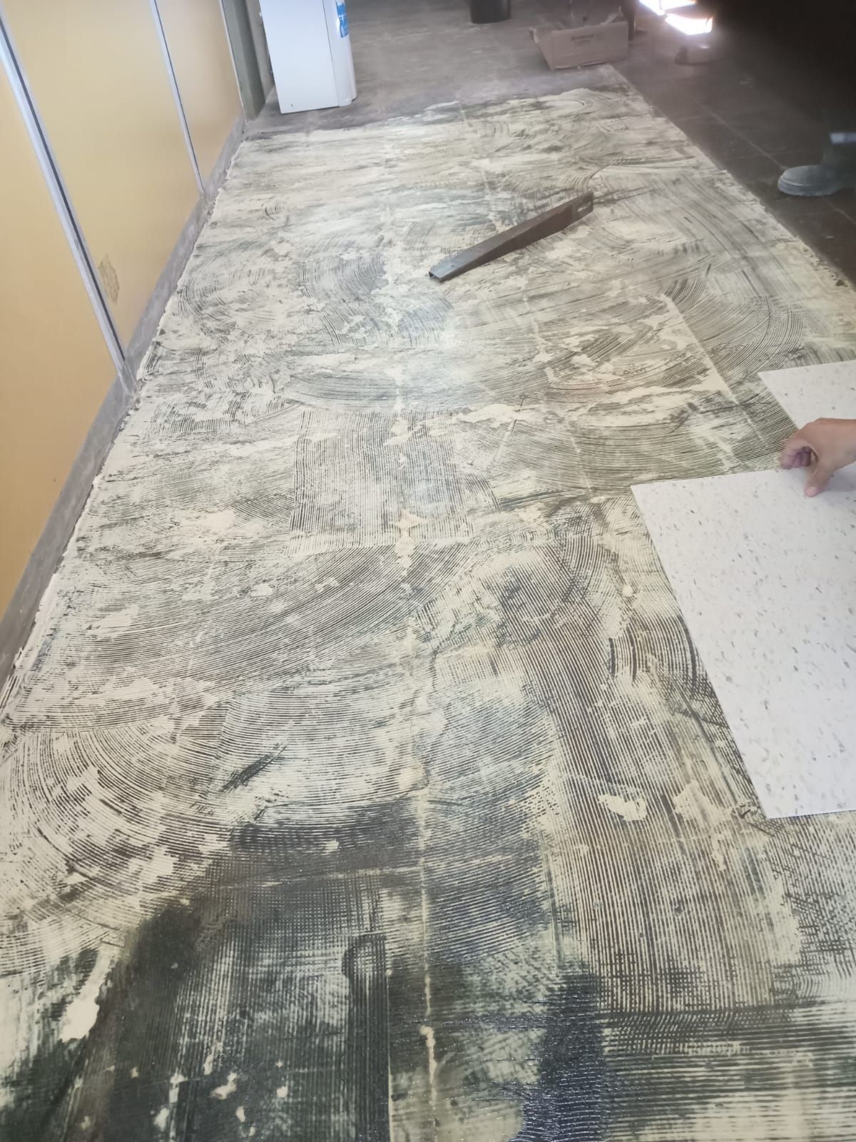 Piso en preparación para la instalación de baldosas, con adhesivo extendido sobre la superficie.