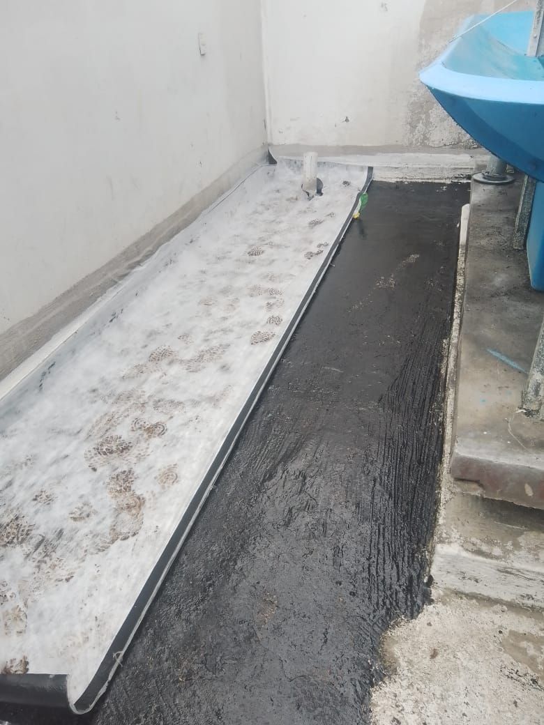 Sección de suelo recién sellada junto a un suelo viejo y desgastado. Baño con lavabo azul.