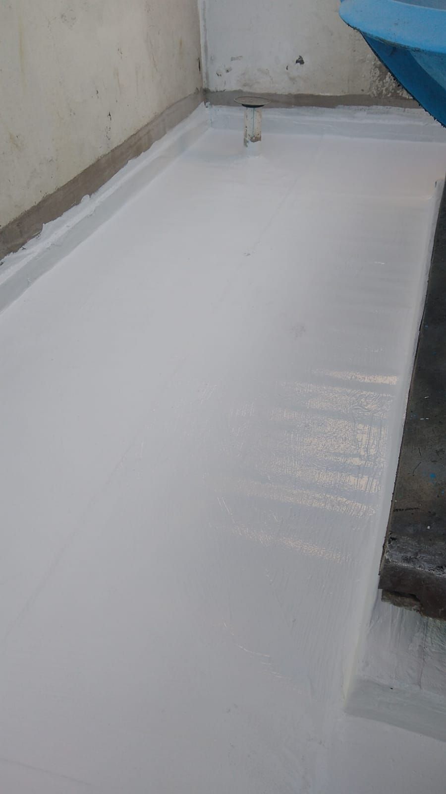 Superficie de azotea pintada de blanco con un muro bajo en el lado izquierdo y un borde oscuro en el lado derecho.