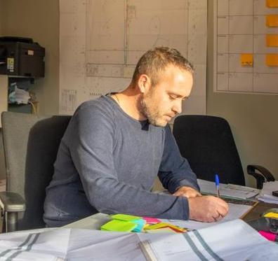 Foto van Marc van Mook werkend aan een tafel.