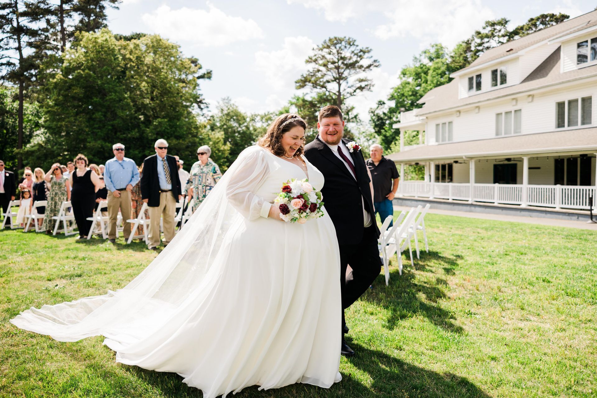 Bride and groom walking down aisle after a wedding ceremony, white dress, holding bouquet.