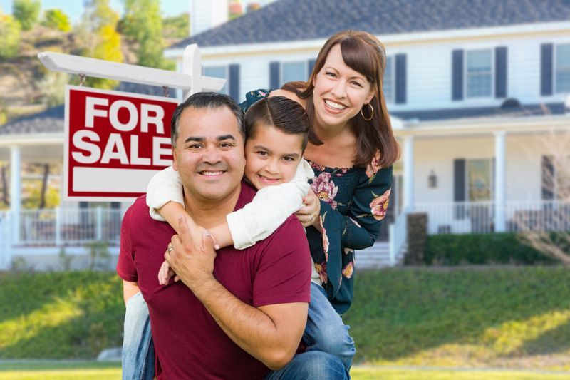 family in front of for sale sign