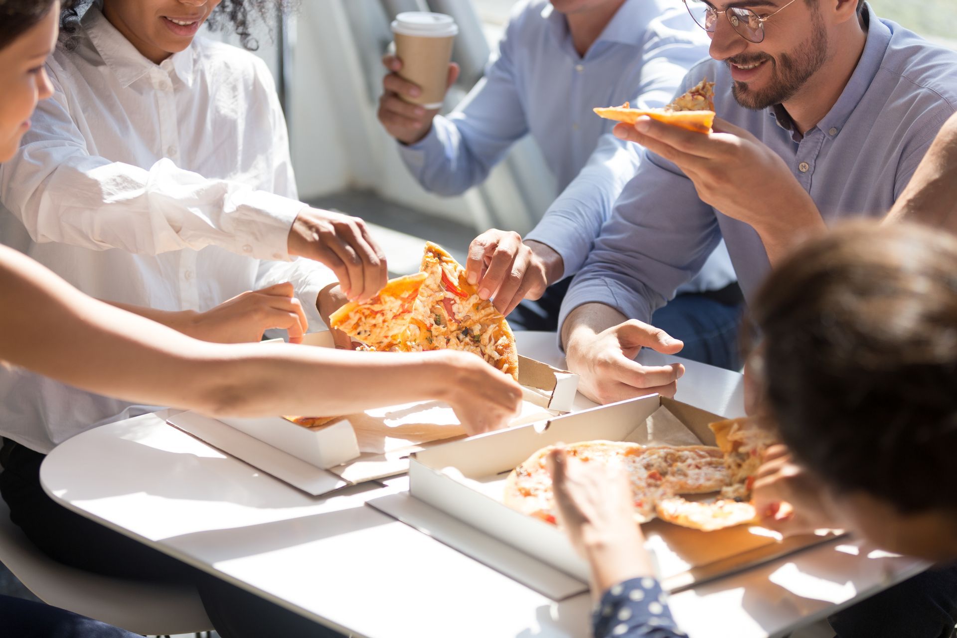 Diverse business office people group taking sharing pizza slices from box on table, staff employees team workers eating together enjoy lunch at work break, delivery service concept, close up view.