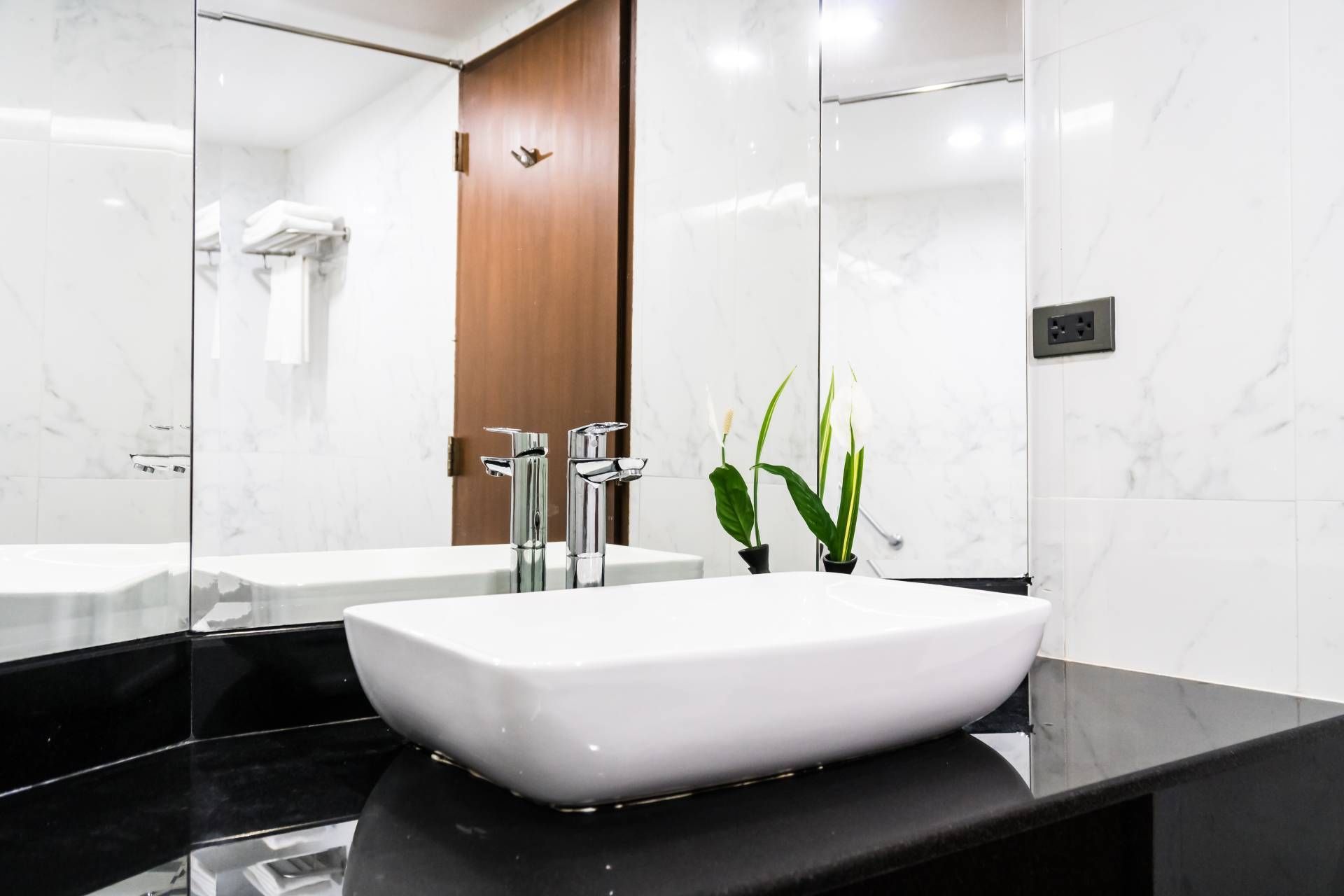 Modern bathroom with white vessel sink, black countertop, and wood cabinet mirror panel