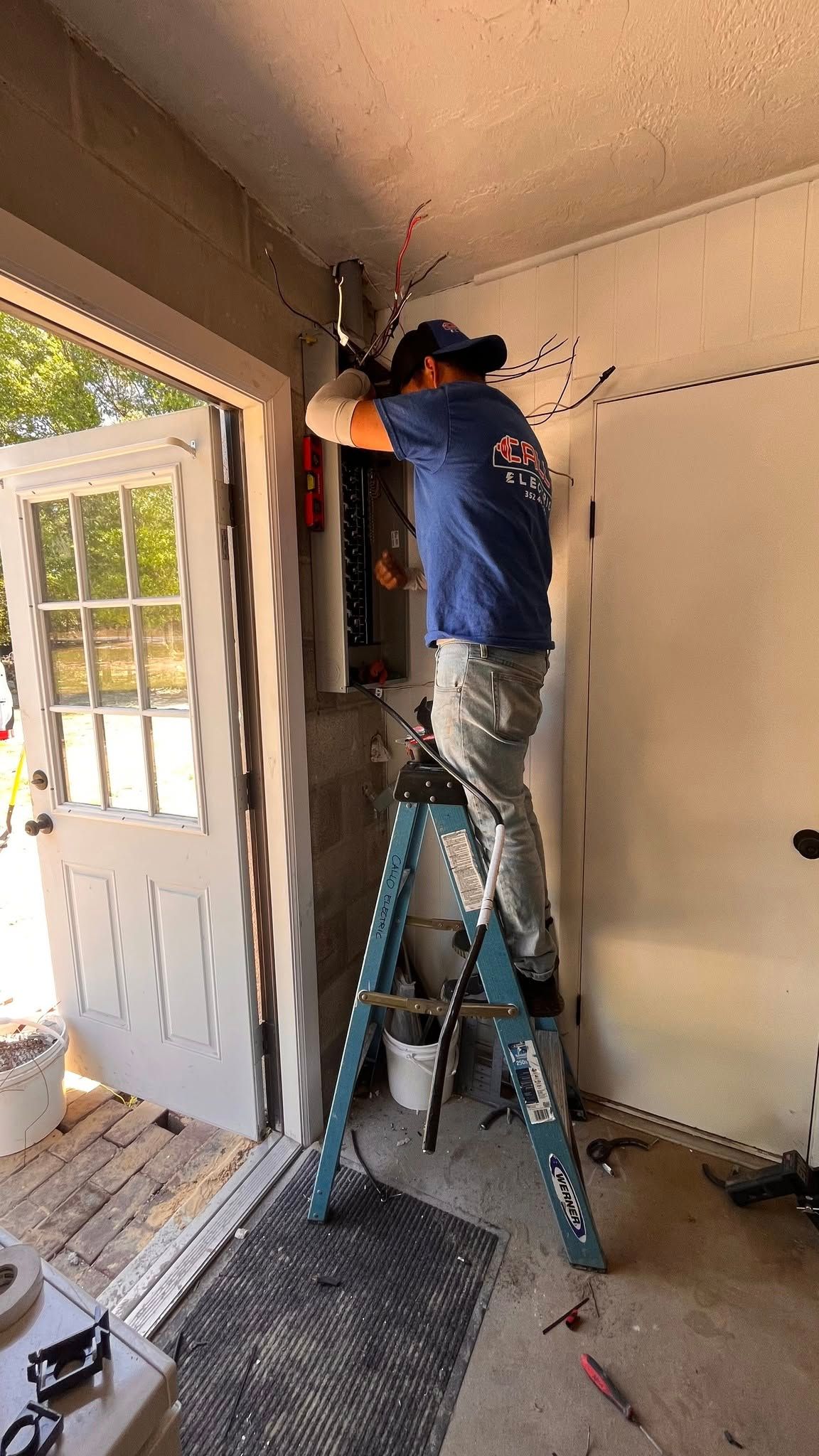 A man is standing on a ladder working on a door.