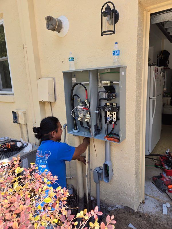 A man in a blue shirt is working on an electrical box on the side of a house.