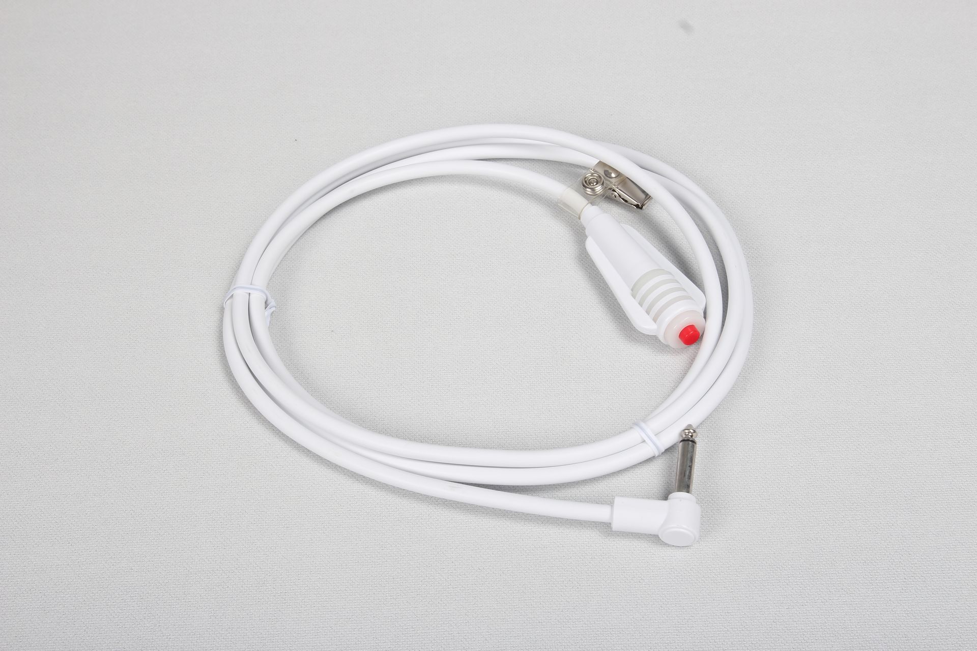 Auf einer weißen Fläche liegt eine weiße Kordel mit einem roten Knopf am Ende.
