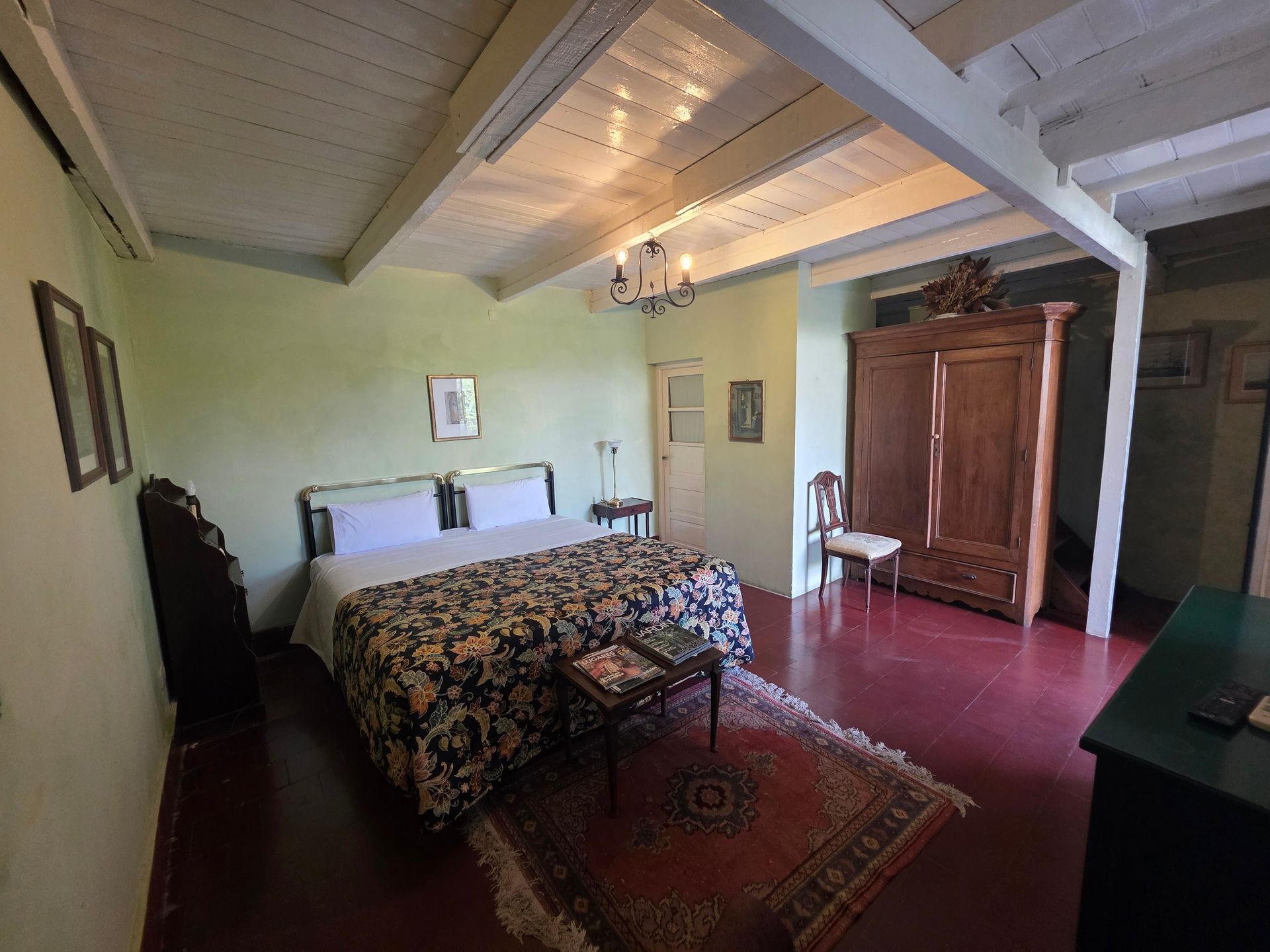 Dormitorio con cama doble, muebles antiguos, suelos de madera y alfombra.