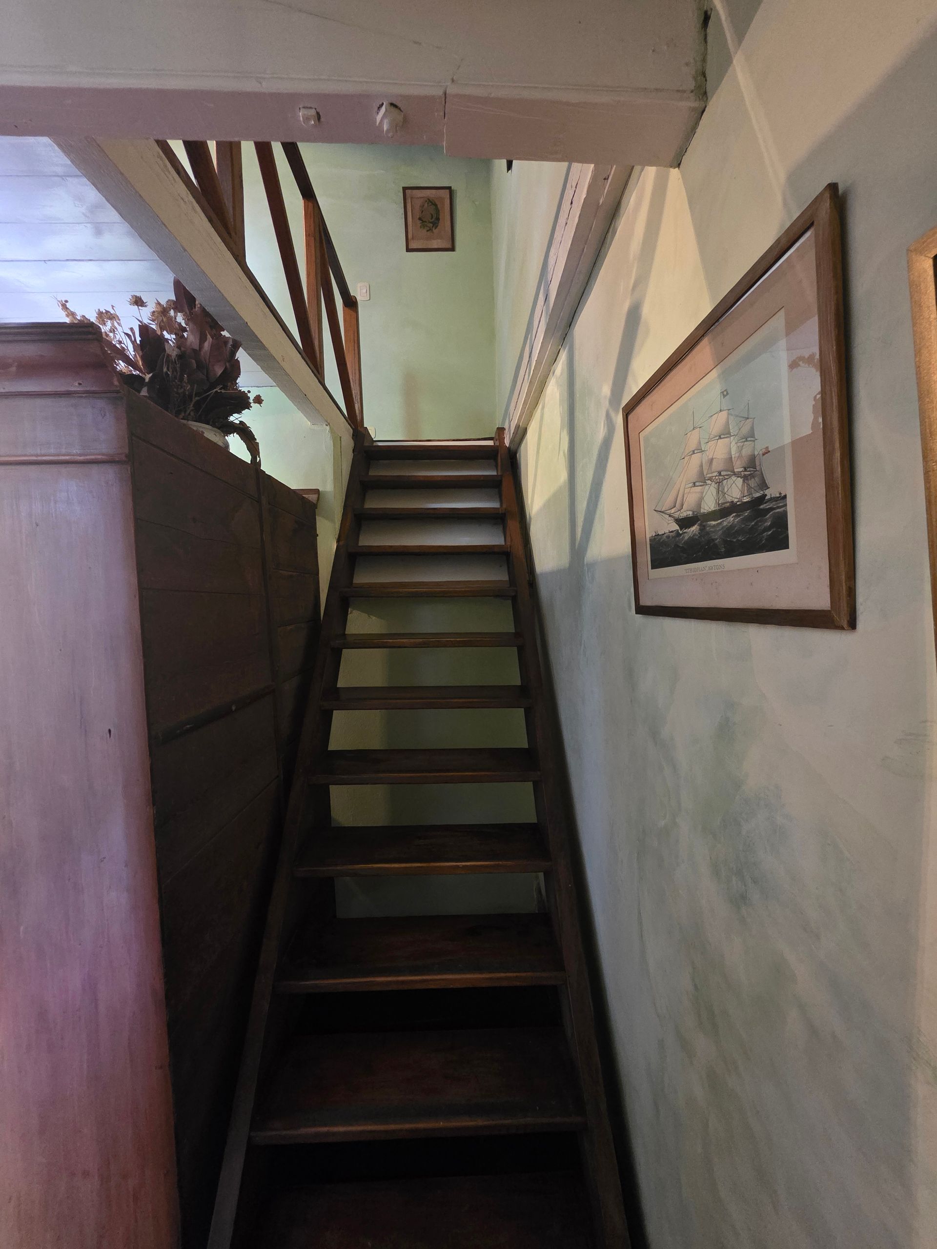 Escalera de madera que sube hacia arriba, con un estampado náutico enmarcado en la pared.