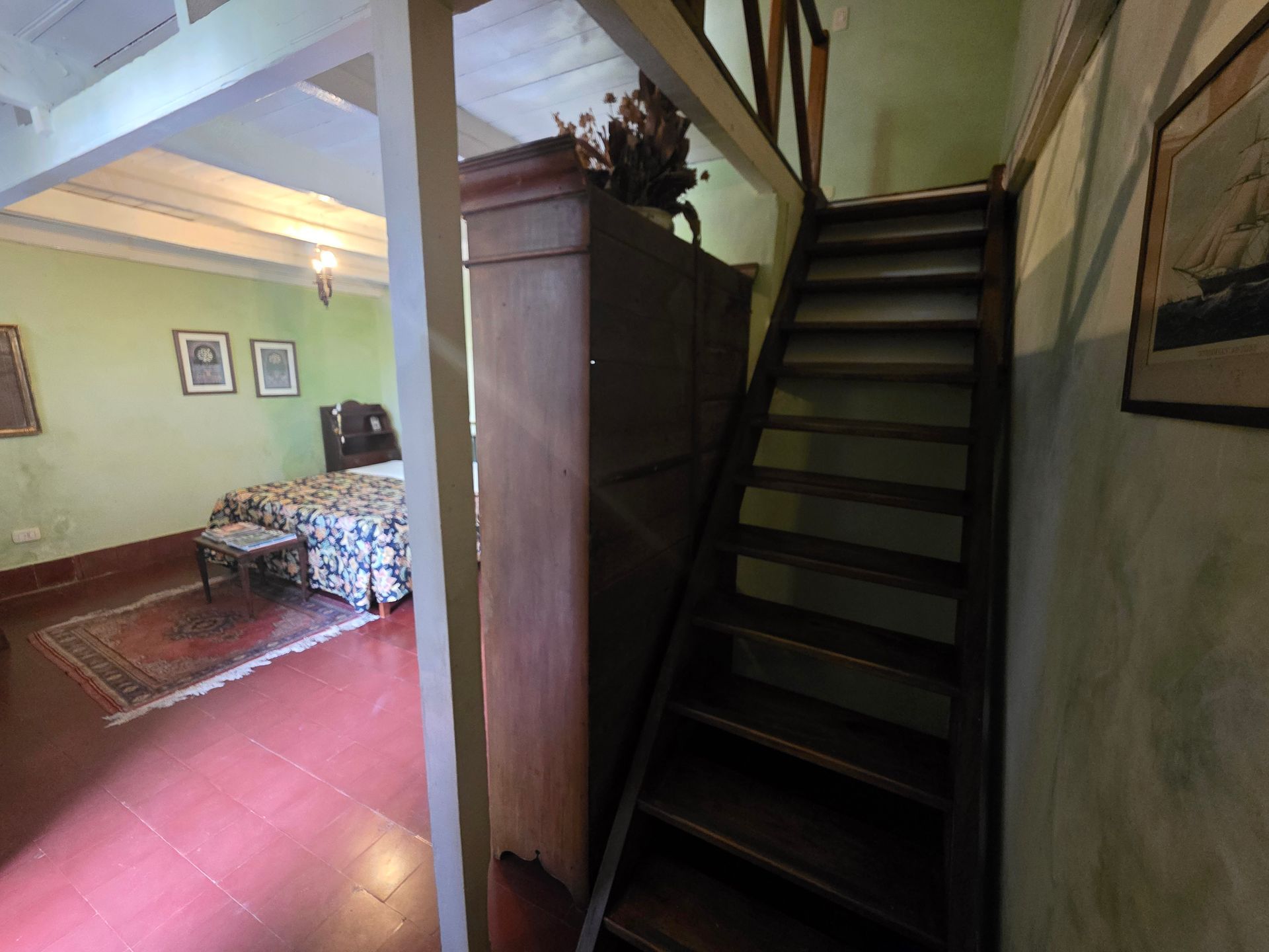 Escalera de madera que sube desde un dormitorio con un gran armario.