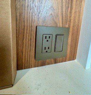 Woman in straw hat smiles, holding wine glass near a lake.