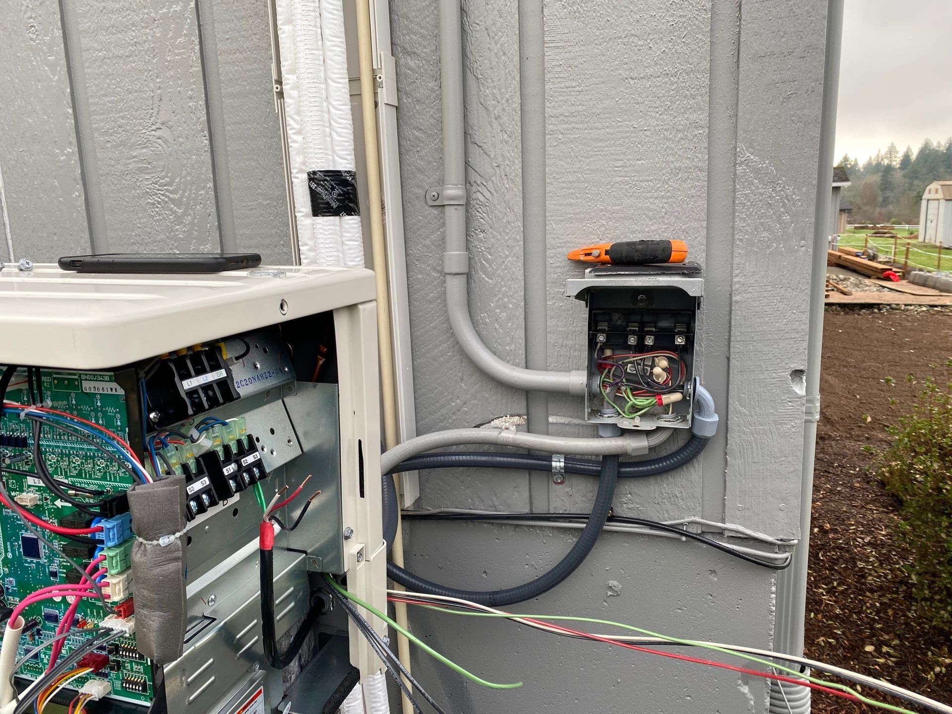 Woman in straw hat smiles, holding wine glass near a lake.