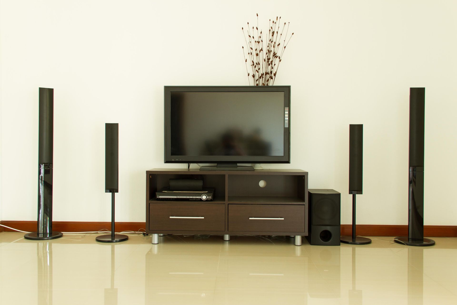 Living room entertainment system: TV on a brown console, surrounded by black speakers.