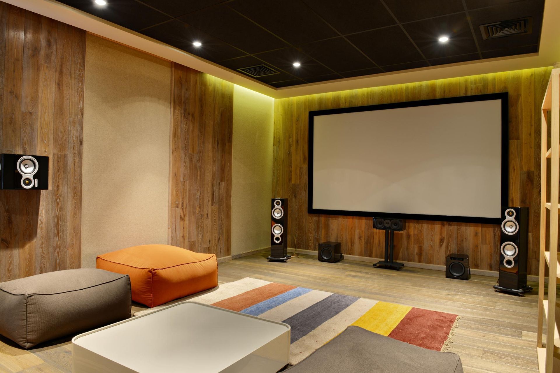 Home theater room with a large screen, speakers, and beanbag seating.