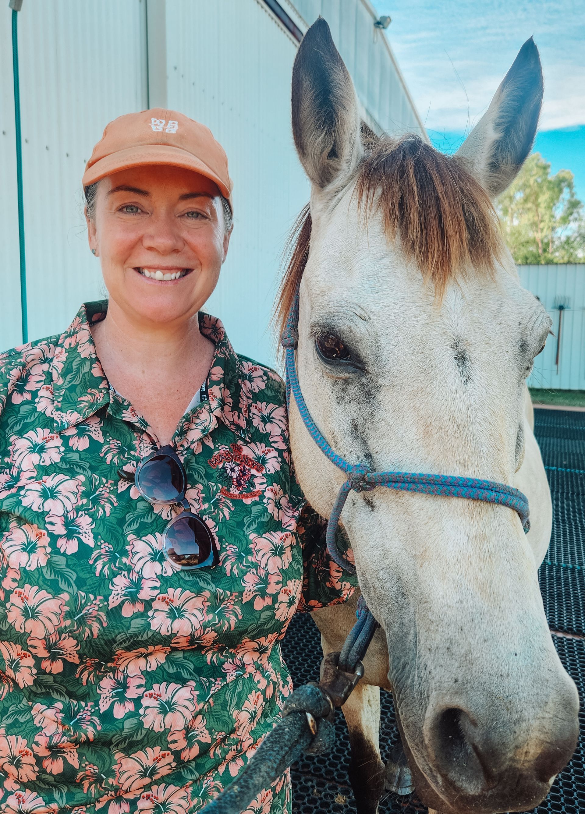 A woman is laying on the ground next to a horse.