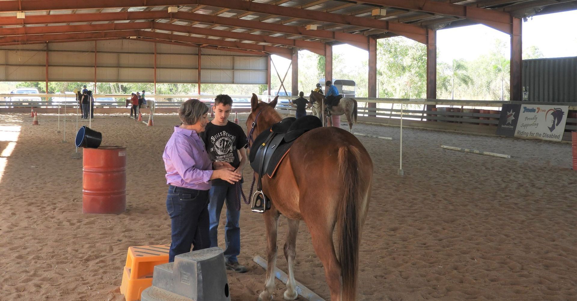 Two girls are standing next to a horse in a barn.