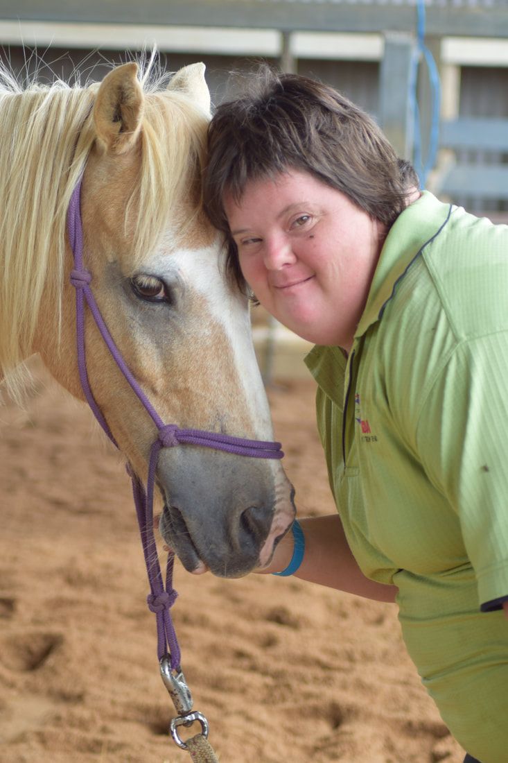 A person and horse with their heads together
